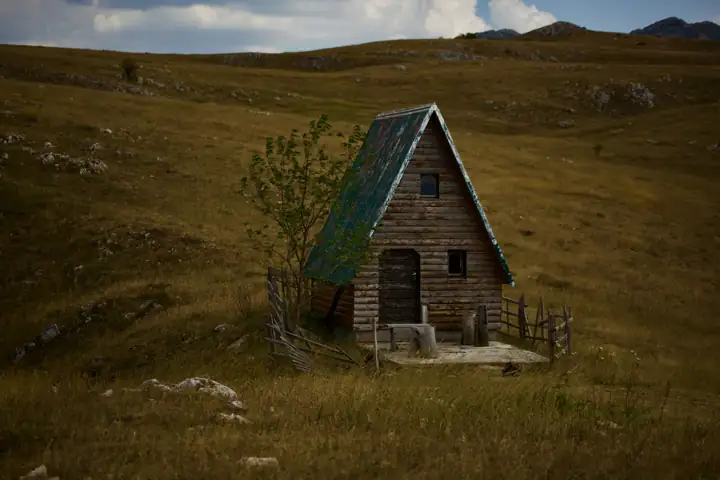 A small wooden cabin alone in a grassy field